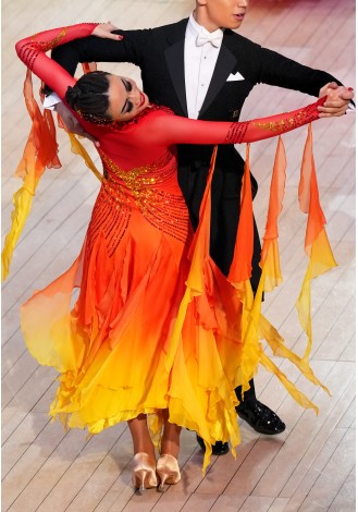 A stunning ombre ballroom dance gown in shades of red, orange, and yellow. The intricate detailing and flowing skirt make it pe