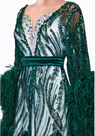 This stunning emerald green ballroom gown features dazzling sequins, long sleeves with dramatic feather accents, and a flatterin