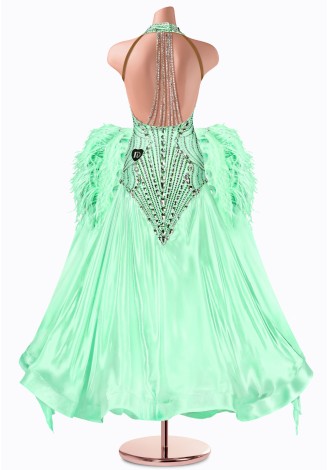 A stunning mint green ballroom dance gown, embellished with sparkling crystals and delicate feather accents. The halter neck an