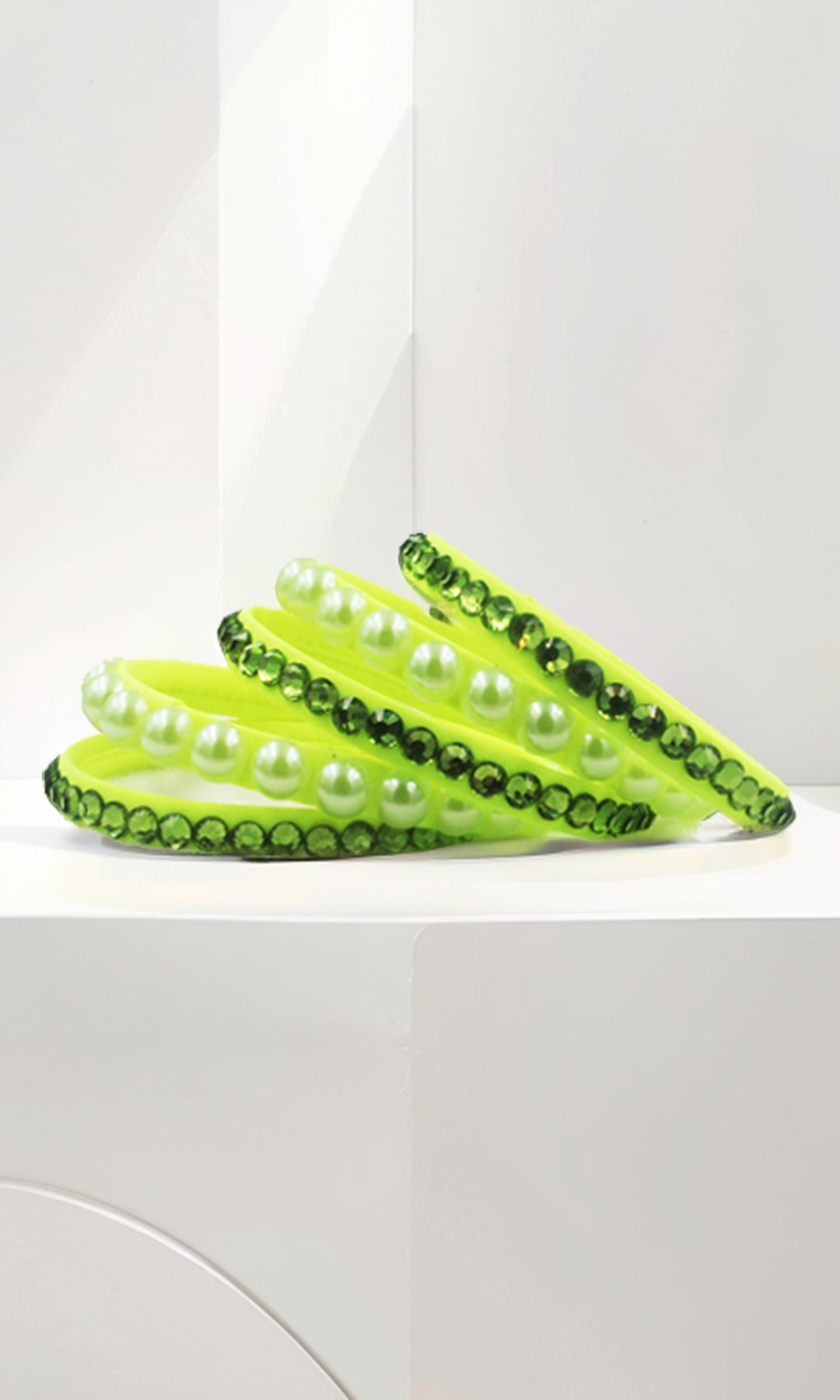 Neon lime green bangles adorned with pearls and dark green crystals. A vibrant and stylish accessory.